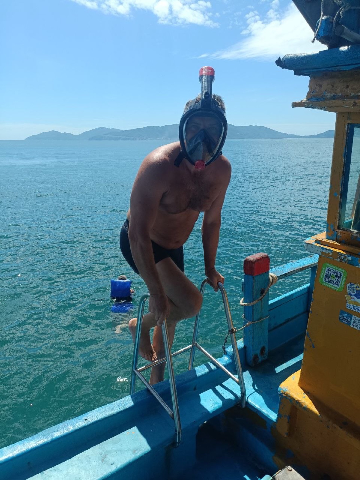 Гость в маске поднимается на лодку из моря